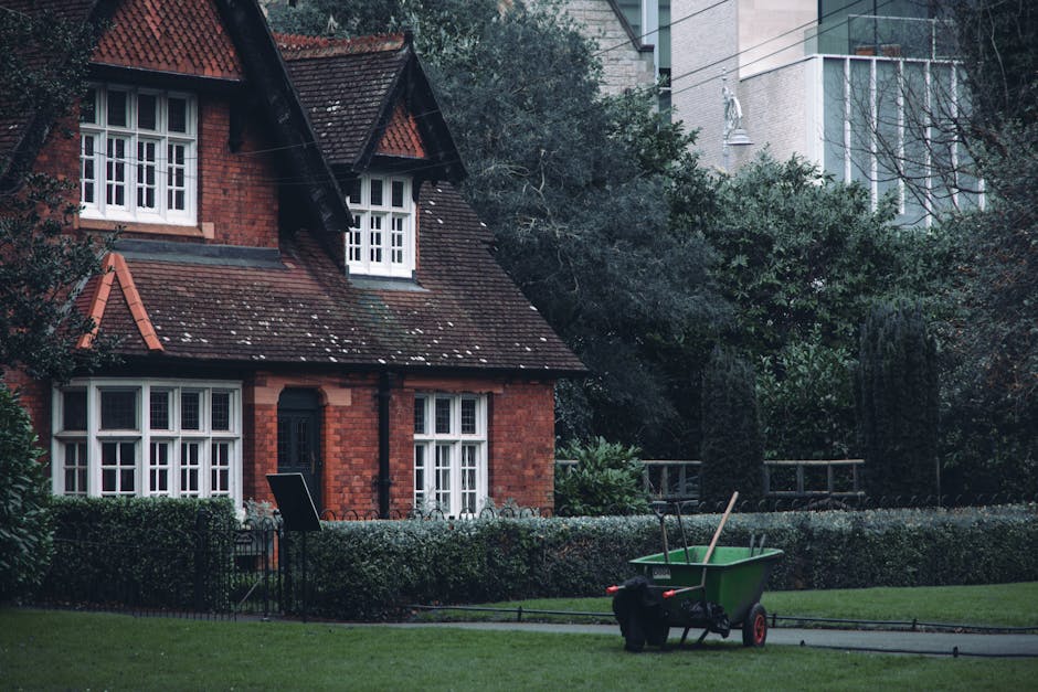 A residential street scene during daytime showing multiple dark grey wheelie bins placed along the pavement in front of brick terraced houses. The bins are lined up in a row, some slightly open with l